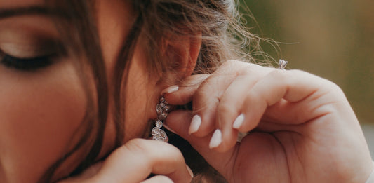 a close up of a person putting on a pair of earrings