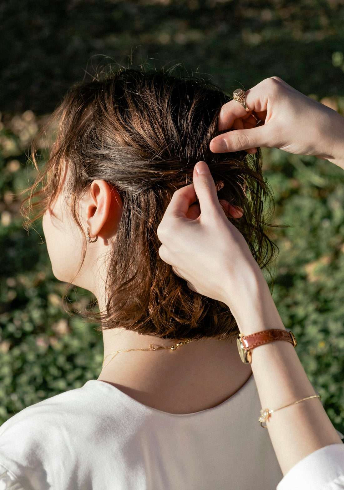 A woman in a white shirt is putting on her hair