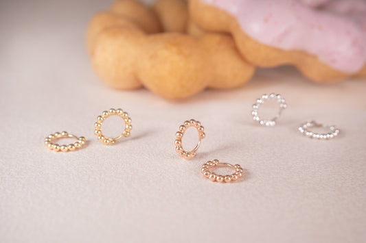 Earrings are displayed with a donut in the background.