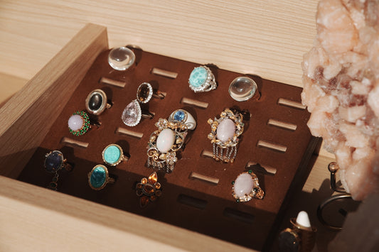 Assortment of decorative rings displayed on a wooden stand.